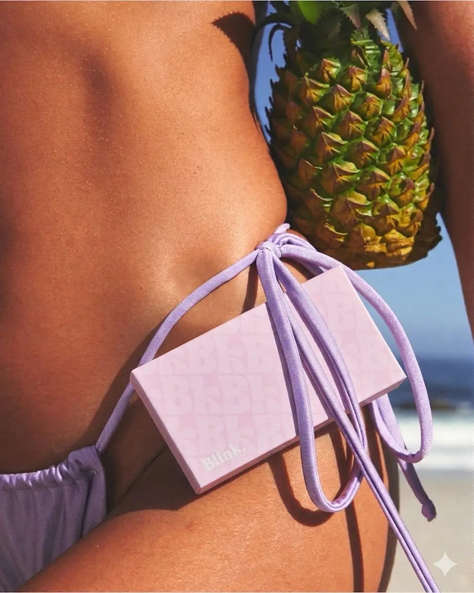 Boîte Blink. faux cils magnétiques yeux de biche rose tenue dans un bikini violet au bord de la plage